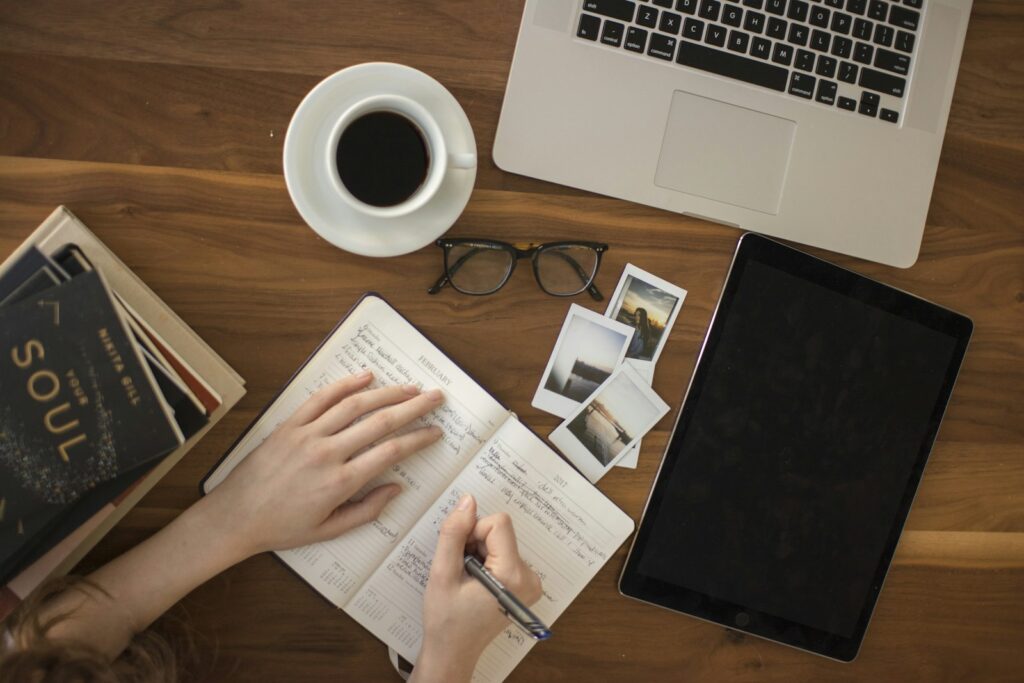 Student writing a literature review at a desk with books, a notebook and a laptop