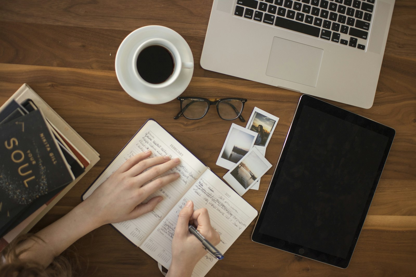 Student writing a literature review at a desk with books, a notebook and a laptop