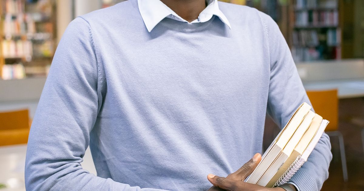 Nigerian student researching with books in the library for a Masters dissertation