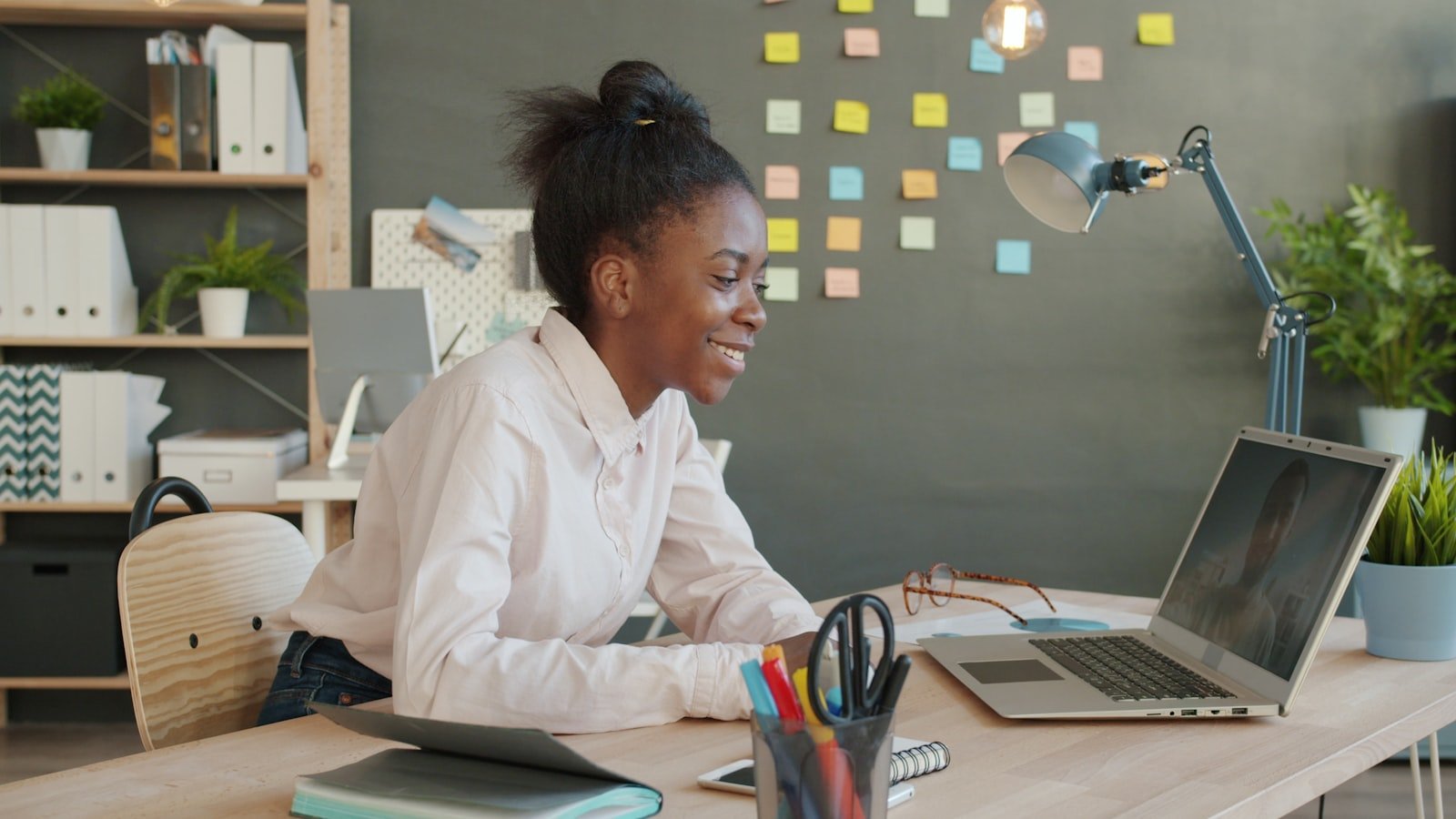 Young African graduate working on a laptop in an office during her UK Graduate Route post study work visa