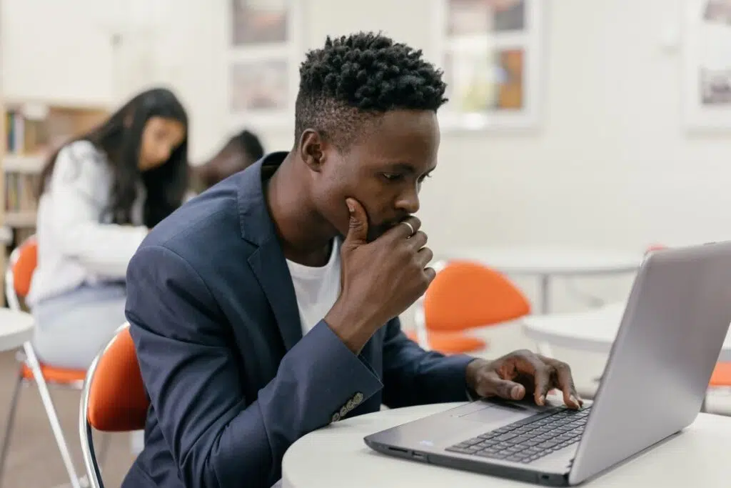 Nigerian student studying his laptop screen closely while checking his JAMB CAPS admission status