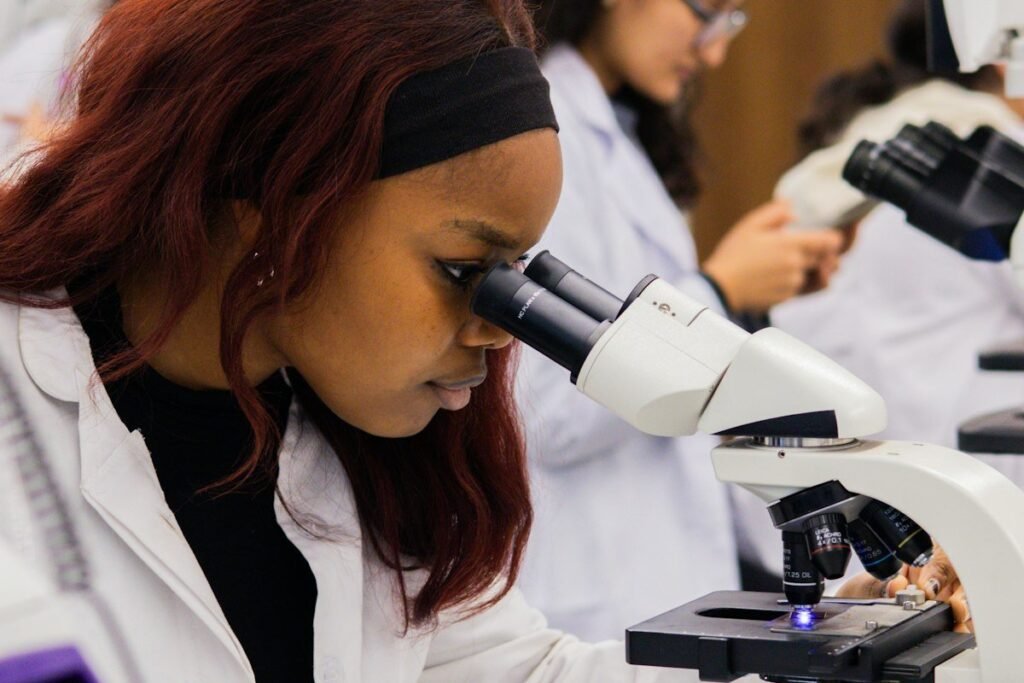 Nigerian science undergraduate looking through a microscope in a university laboratory