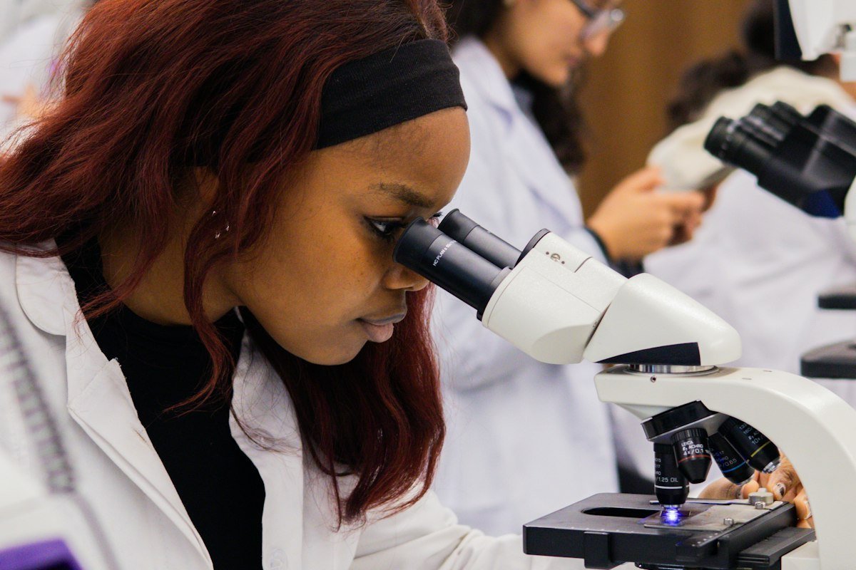 Nigerian science undergraduate looking through a microscope in a university laboratory