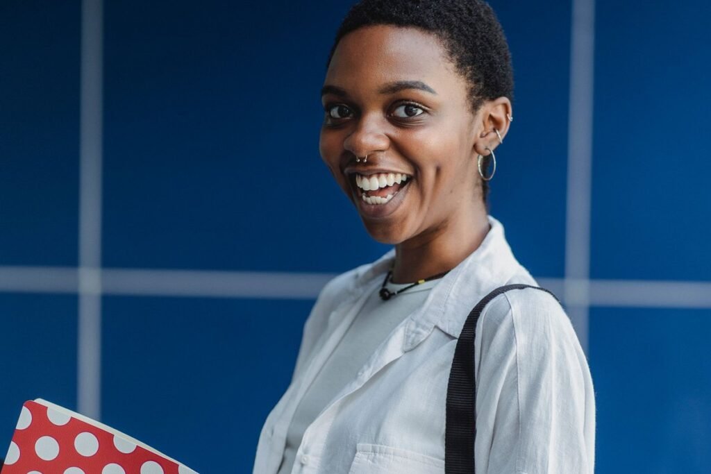 Smiling young Nigerian student with notebooks and a bag strap, weighing whether to take the NELFUND loan