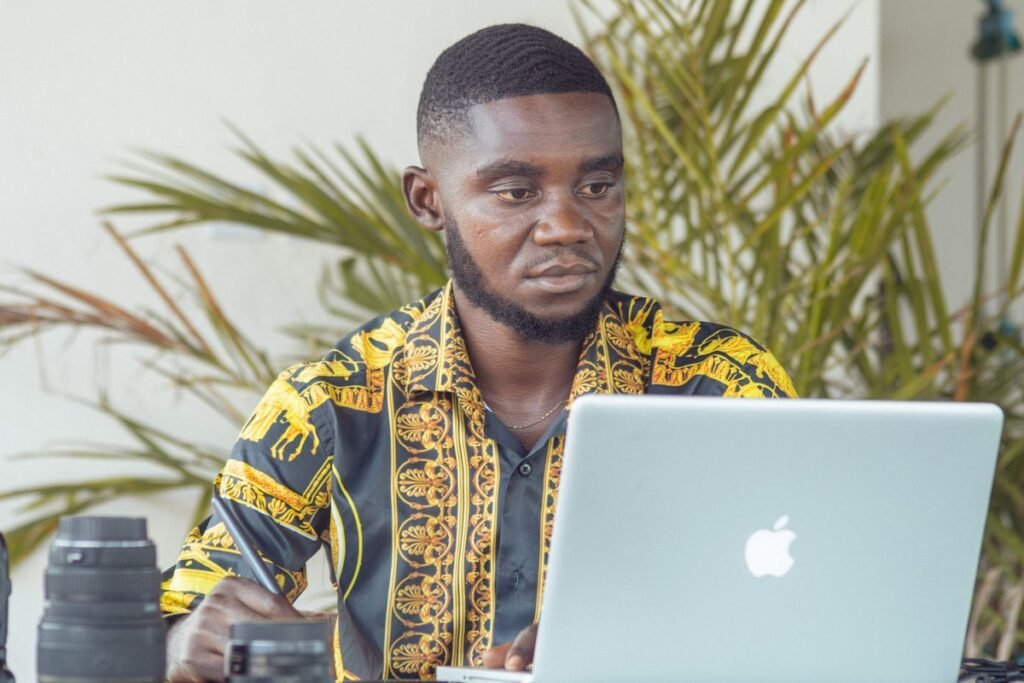 Young Nigerian graduate checking his records at a laptop before applying for the JAMB NIN alignment service