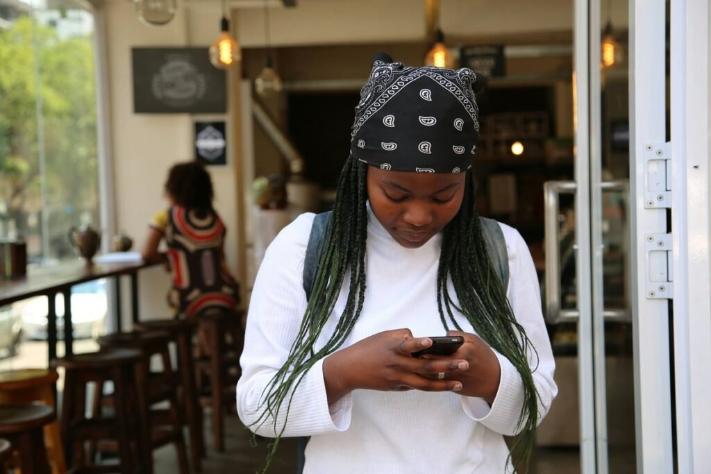 Young Nigerian graduate checking her NYSC dashboard on her phone for redeployment