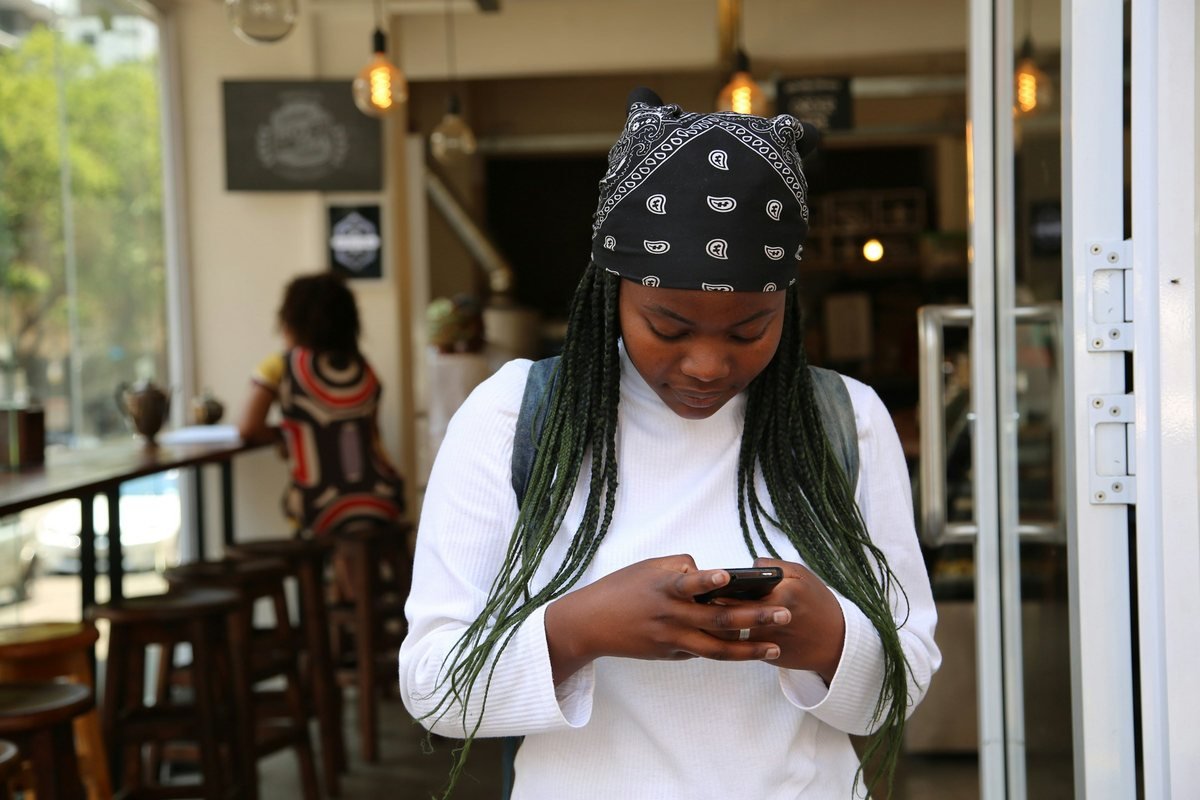 Young Nigerian graduate checking her NYSC dashboard on her phone for redeployment